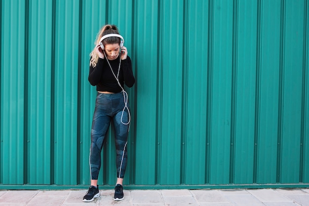 Fit woman with headphones on blue