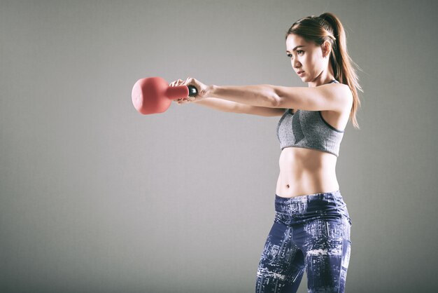 Fit young Asian woman exercising with kettlebell 