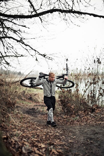 Fit young man walking with bicycle on trail