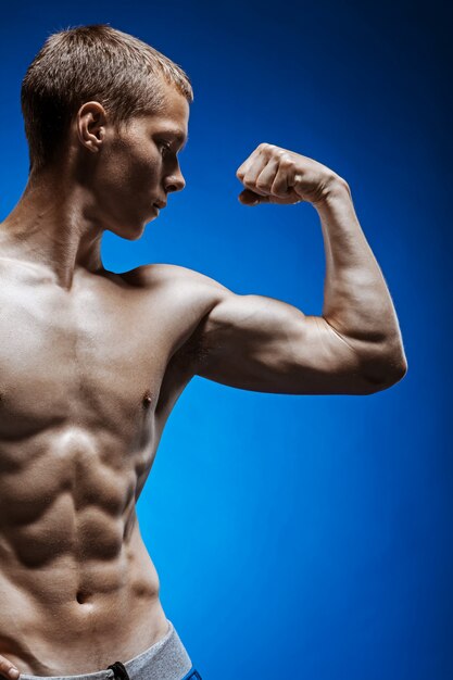 Fit young man with beautiful torso on blue wall