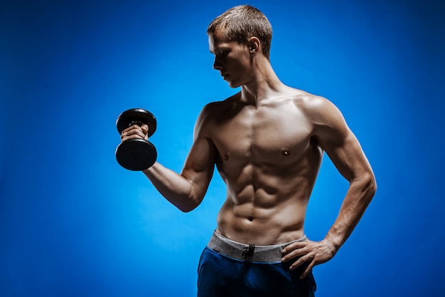 Giovane adatto con il bello torso sulla parete blu