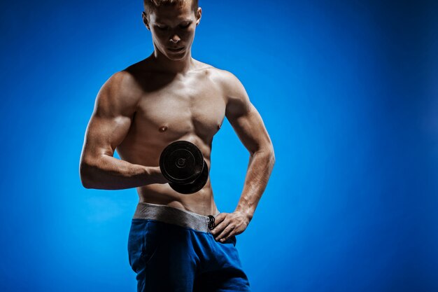 Fit young man with beautiful torso on blue wall