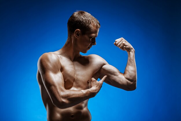 Fit young man with beautiful torso on blue