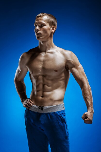 Fit young man with beautiful torso on blue