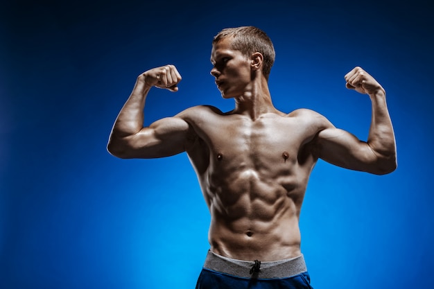 Fit young man with beautiful torso on blue