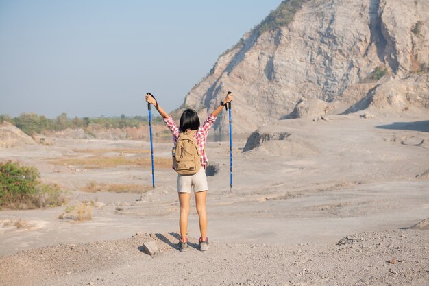 fit young woman hiking in the mountains standing on a rocky summit ridge with backpack