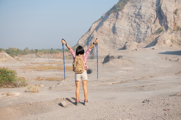 バックパックで岩だらけの頂上の尾根に立っている山でハイキングする若い女性に合う