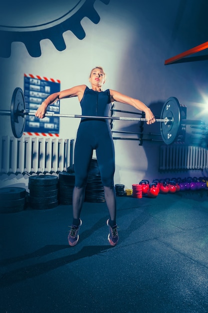 Foto gratuita montare la giovane donna sollevamento bilancieri lavorando in una palestra