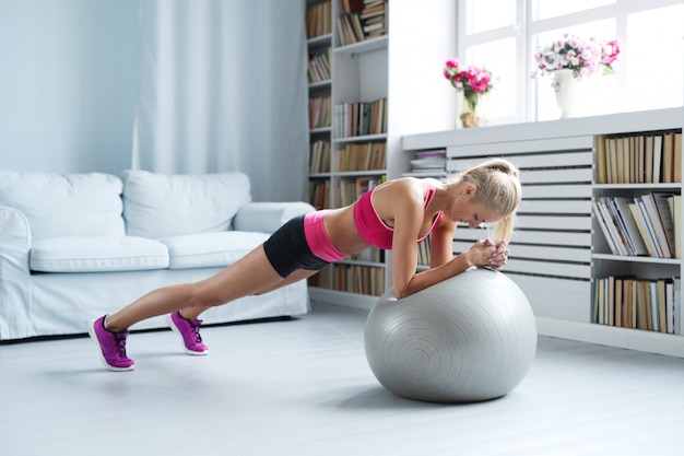 Женщина фитнеса делая простирания с ее шариком тренировки дома