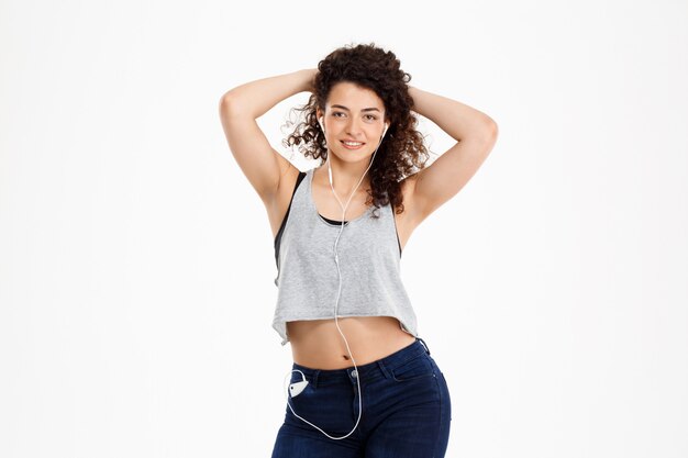 Fitness curly girl listening to music and posing