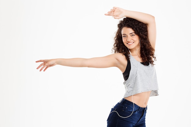 Fitness curly girl listening to music and posing