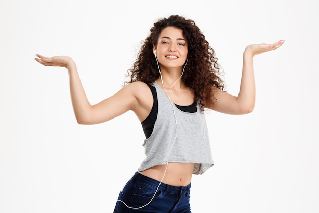 Fitness curly girl listening to music and posing