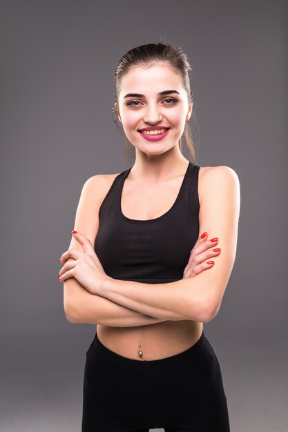 Fitness female woman with muscular body ready for workout on grey wall