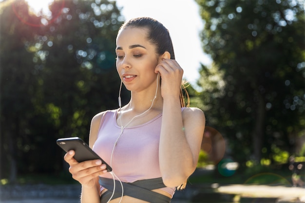 Fitness girl listening to music stands on the street