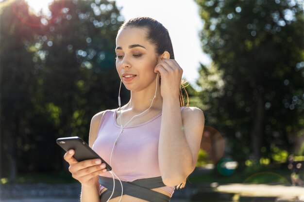 音楽を聴くフィットネス女の子が通りに立っています。