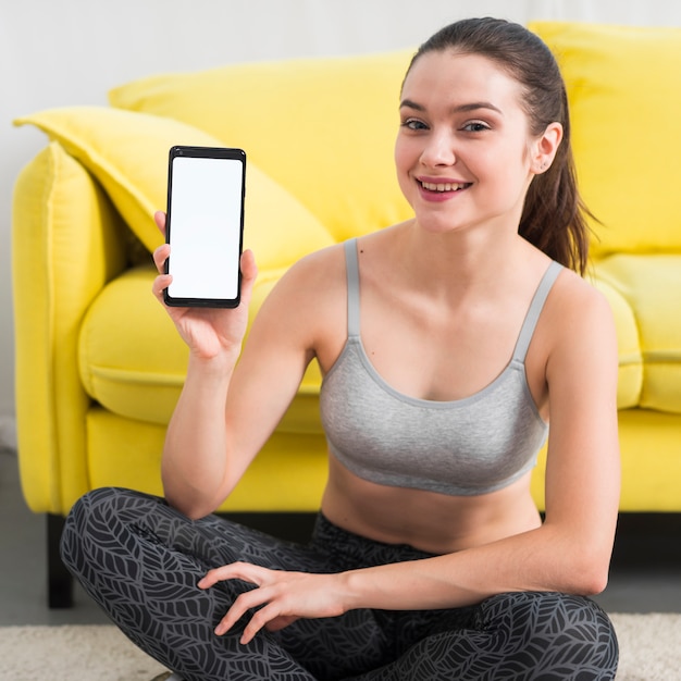 Free photo fitness girl showing mobile phone