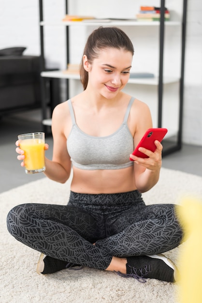 Foto gratuita ragazza di forma fisica che per mezzo del suo telefono cellulare