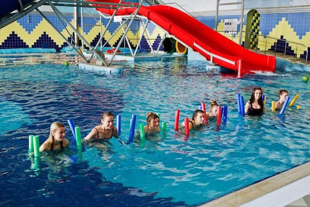 Foto gratuita gruppo fitness di ragazze che fanno esercizi aerobici in piscina presso il parco acquatico attività sportive e ricreative