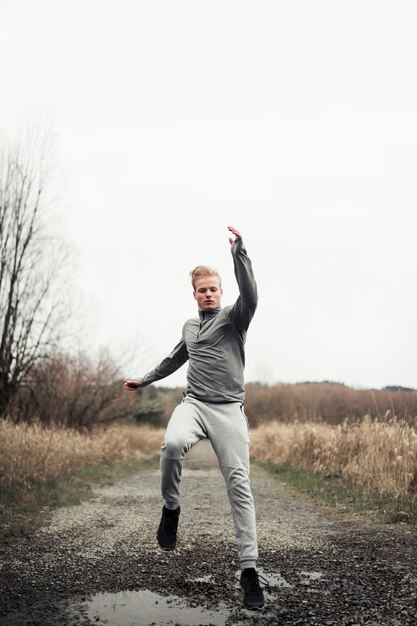 Fitness male athlete running on dirt road in the field