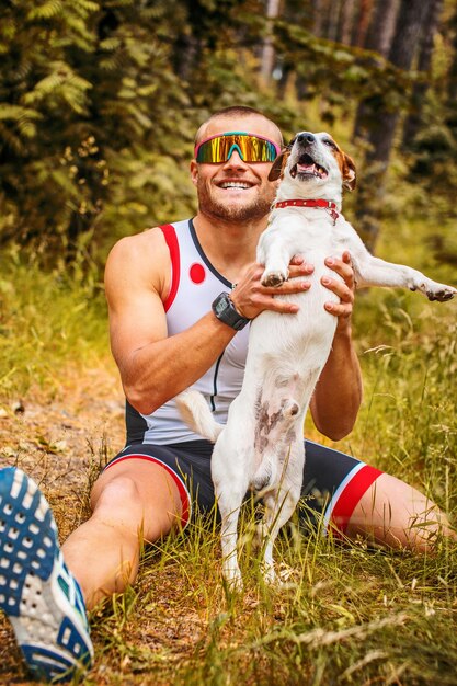 森の中で彼の犬と一緒にスポーツウェアのフィットネス男。