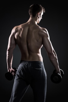 Фитнес-мужчина, показывающий его ужасное тело с гантелями, вид сзади