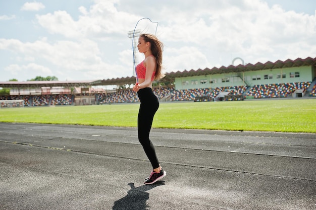 Fitness sporty girl in sportswear at a football stadium outdoor sports Happy sexy woman workout and jumping with rope