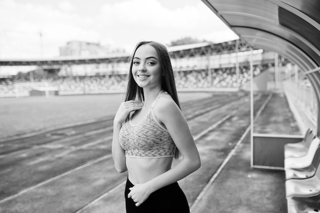 スタジアムの屋外スポーツでスポーツウェアのフィットネススポーティな女の子コーチトリビューンで幸せなセクシーな女性