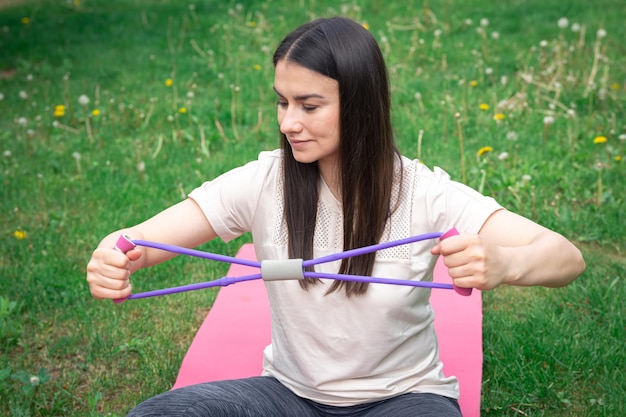 Foto gratuita donna di forma fisica che si esercita con l'elastico di forma fisica all'aperto
