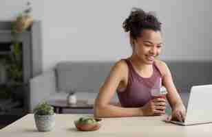 Free photo fitness woman having a fruit juice while using a laptop