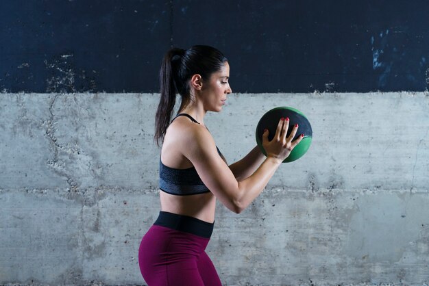 Женщина фитнеса, держащая медицинский мяч и упражнения в тренажерном зале