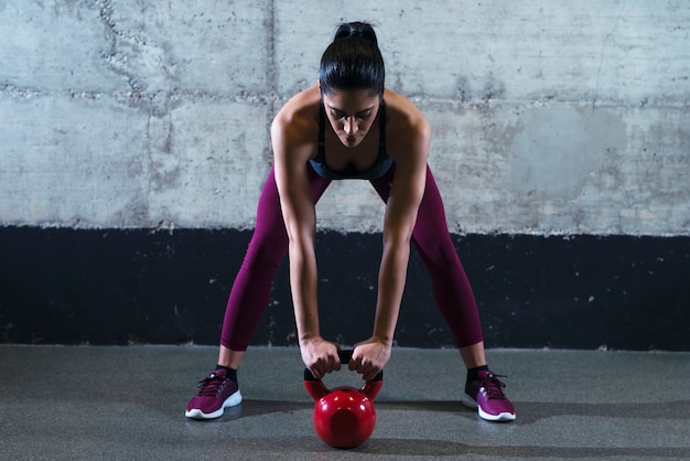 Free photo fitness woman in sports clothes exercising with kettle bell weight in the gym