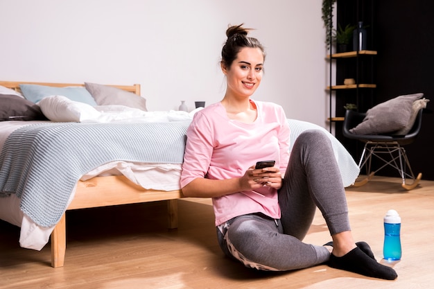 Foto gratuita donna di forma fisica che per mezzo del telefono cellulare