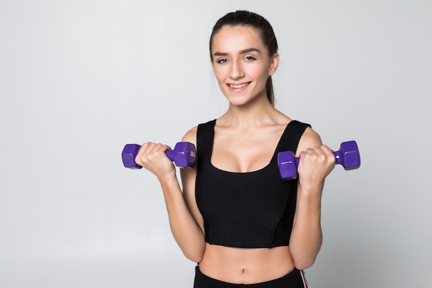 Fitness woman with dumbbell isolated on white wall.