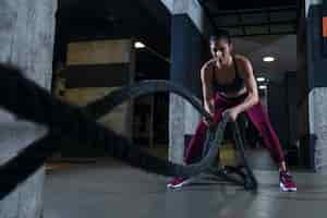 Foto gratuita donna di forma fisica che risolve con le corde di battaglia in palestra