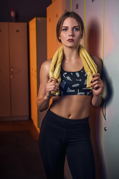 Free photo fitness young beautiful woman with towel resting in dressing room. dressed in sport clothes. gym