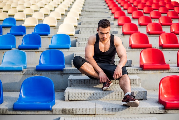 Foto gratuita giovane atleta maschio di forma fisica che si rilassa sulla gradinata