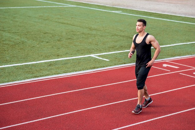 Fitness young male athlete running on race track