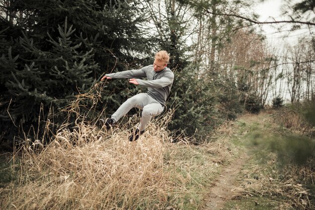 Fitness young man jumping over the dry grass