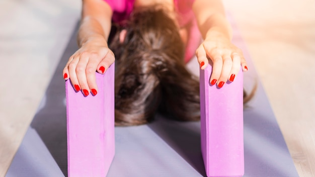 Fitness young woman doing stretching exercise with pink blocks