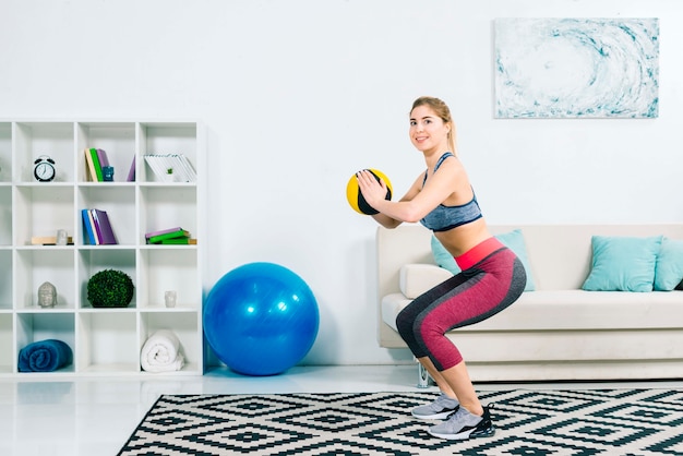 Fitness young woman exercising with medical ball in gym at home