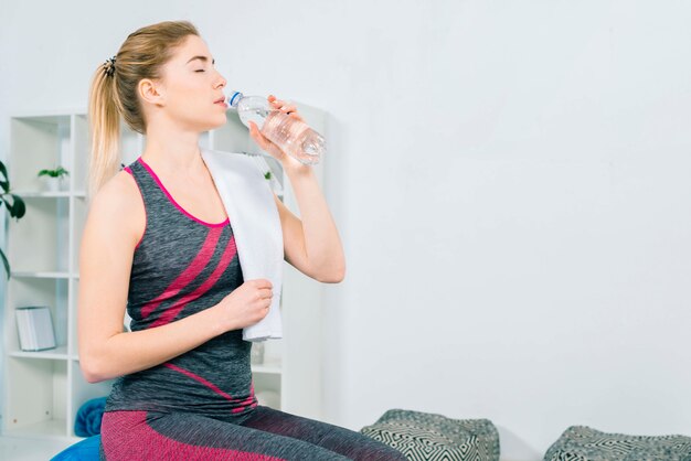 Fitness young woman in sportswear drinking water from bottle