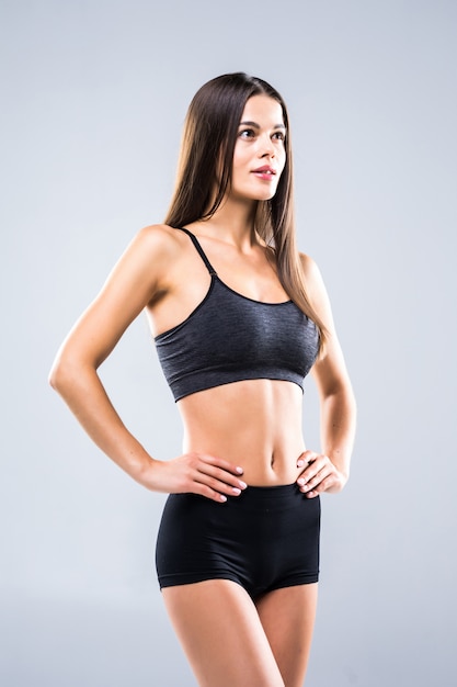 Fitness young woman standing isolated on gray