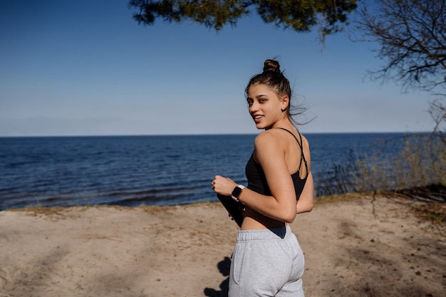 La giovane donna di forma fisica cammina nel parco e nella posa per la macchina fotografica