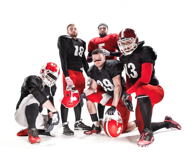 Foto gratuita i cinque giocatori di football americano in posa con la palla su sfondo bianco