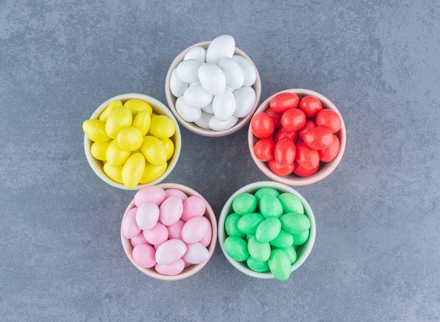 Five bowls of gum, on the marble background. 