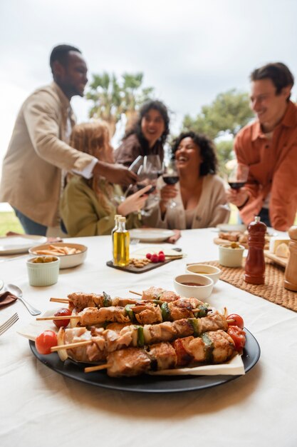 Five friends toasting with glasses of wine and eating barbeque during outdoor party