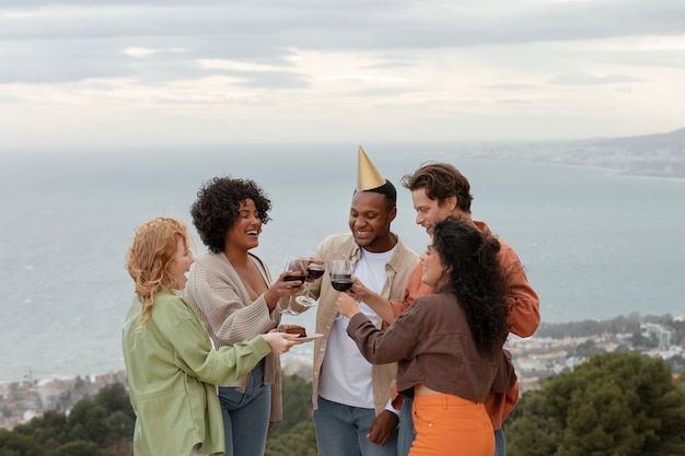 Foto gratuita cinque amici brindano con bicchieri di vino e sorridono durante la festa all'aperto