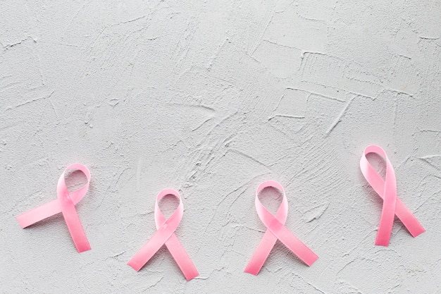 Five pink ribbons on plaster background