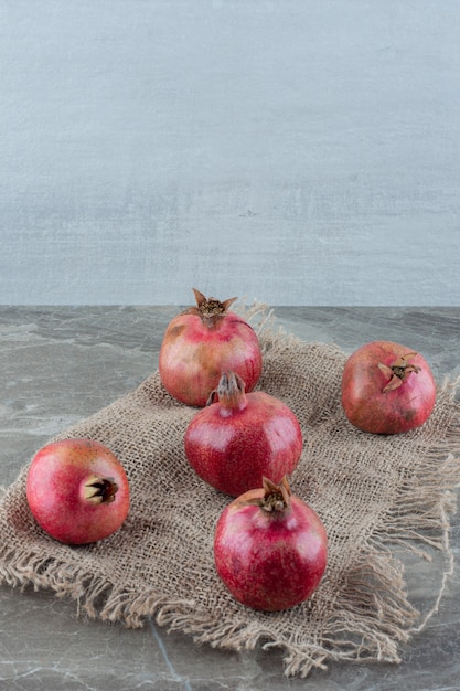 Five pomegranates on a piece of cloth on marble.