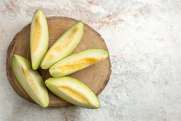 Five slices of melon on wooden platter on left side of marble ground